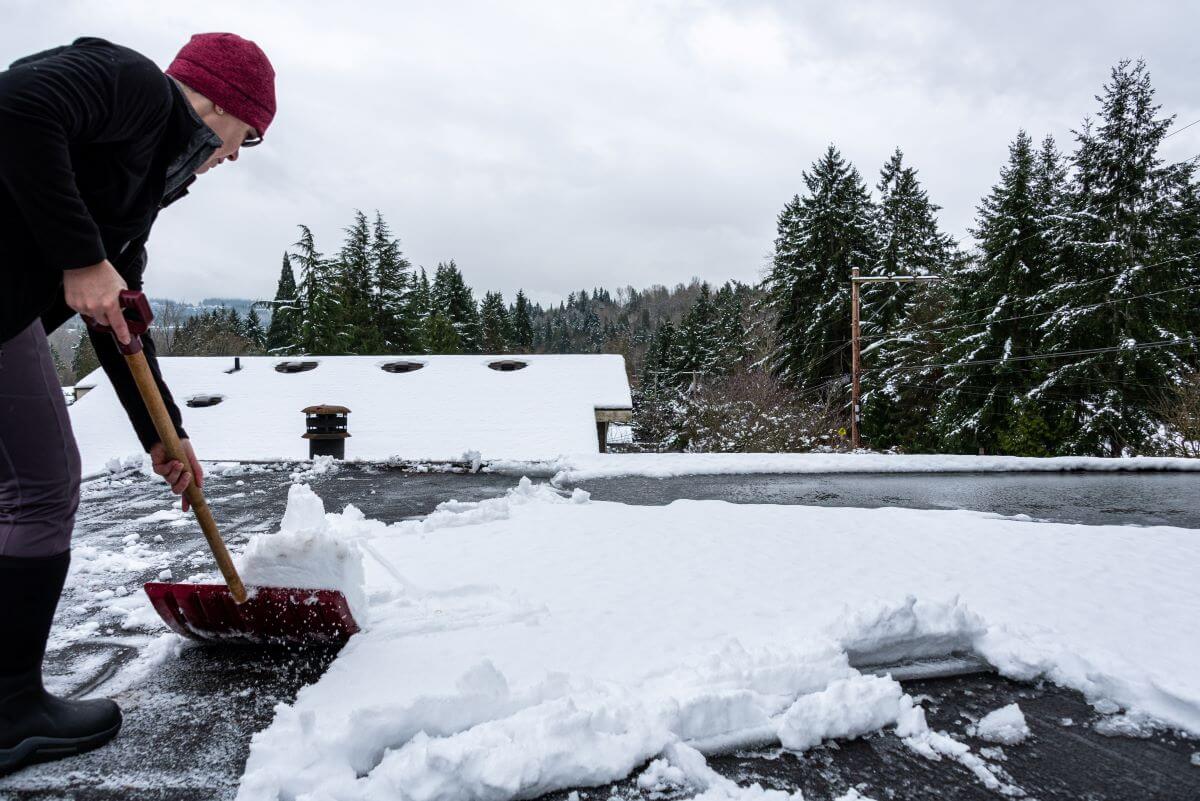 Flat Roofer Clearing Snow in Winter | getflatroofing.com 