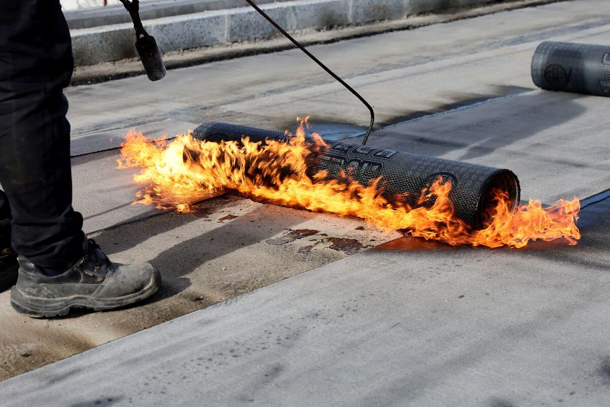 Flat Roof Installer pictured torching down modified bitumen roofing